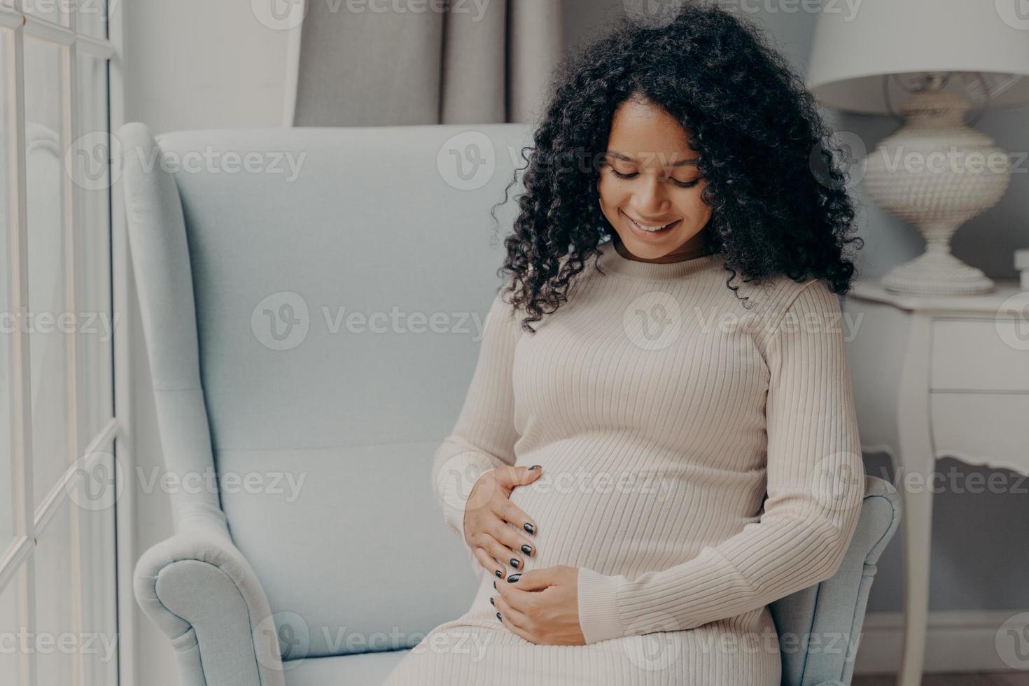 hübsche afroamerikanische frau, die ihren bauch in erwartung eines zukünftigen babys hält foto