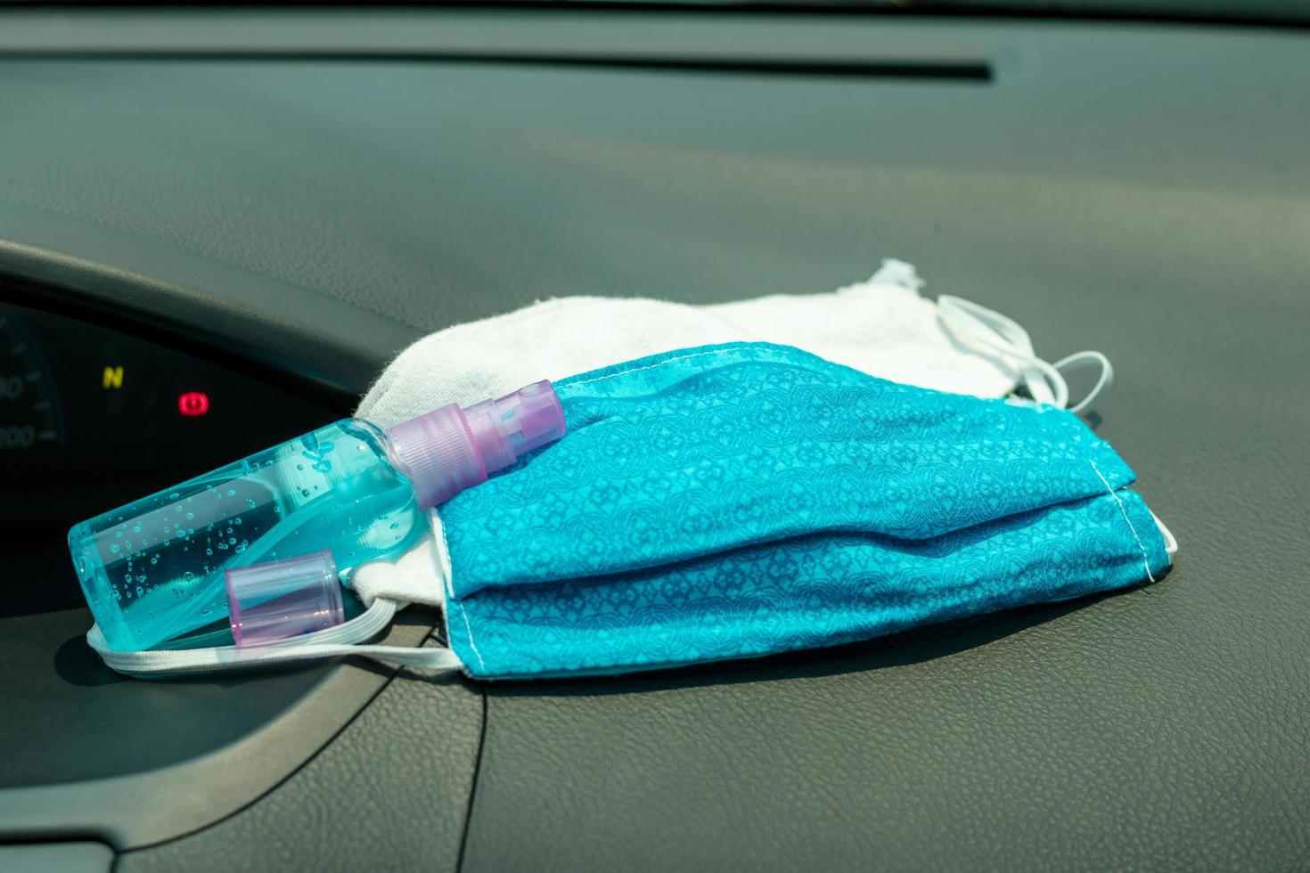 Stoffmaske mit einer Flasche Gel im Auto. foto