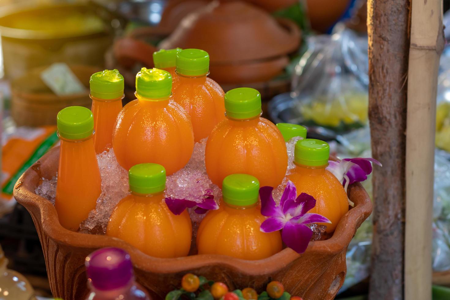 Flasche Orangensaft in Eis mit Schmetterlingserbsenblumen. foto