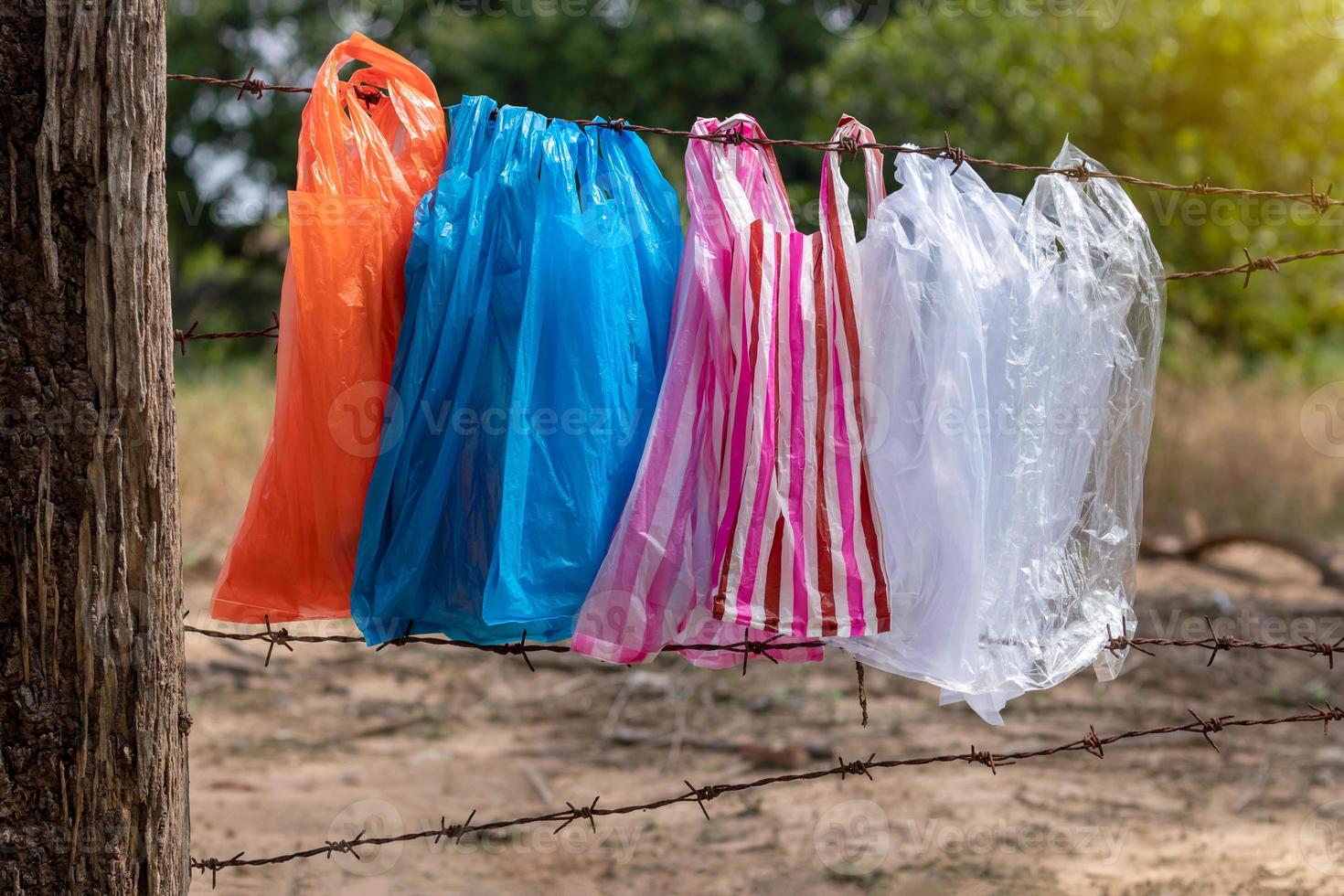 Eine Vielzahl von Plastiktüten, die am Stacheldrahtzaun hängen. foto