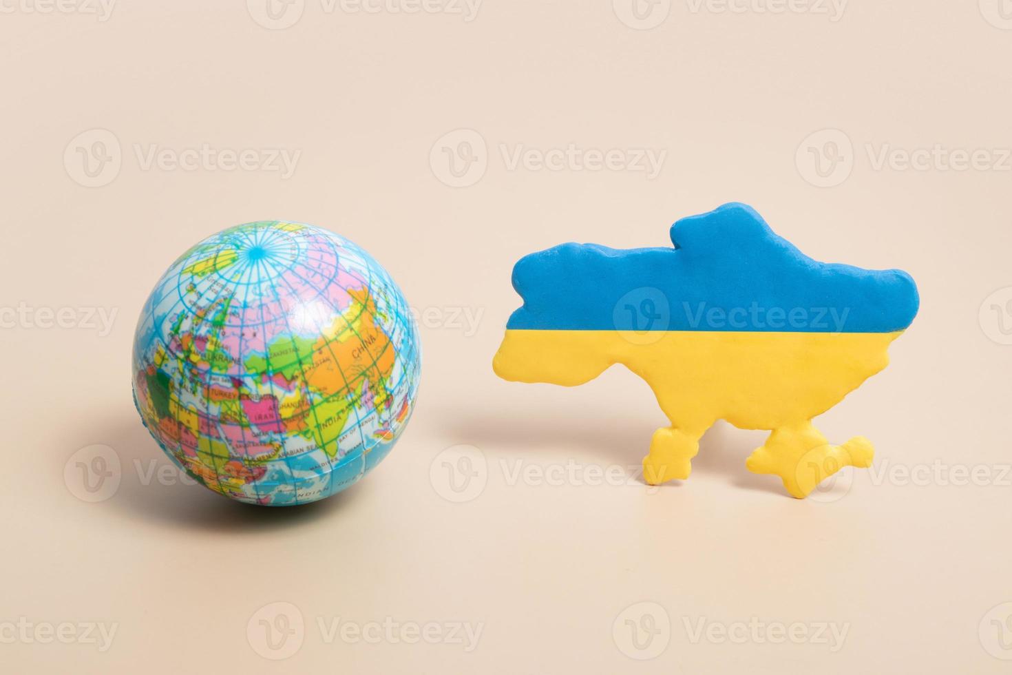 plastilingelbe und blaue karte der ukraine und des planeten erde in der nähe foto