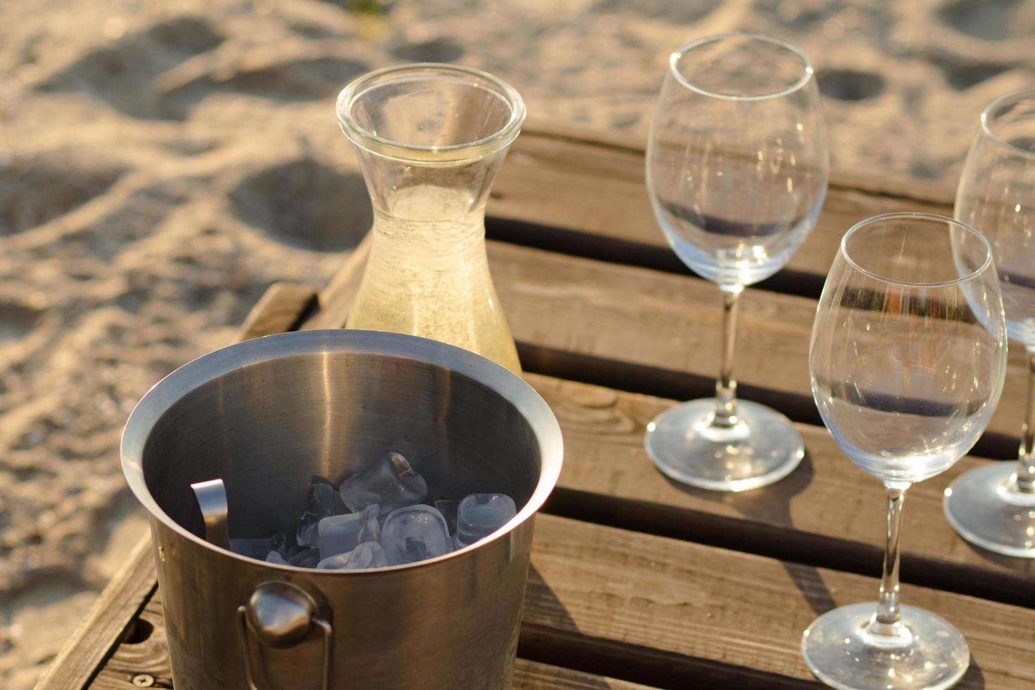 flasche wein, gläser und eis auf holztisch, sommerstrandhintergrund foto