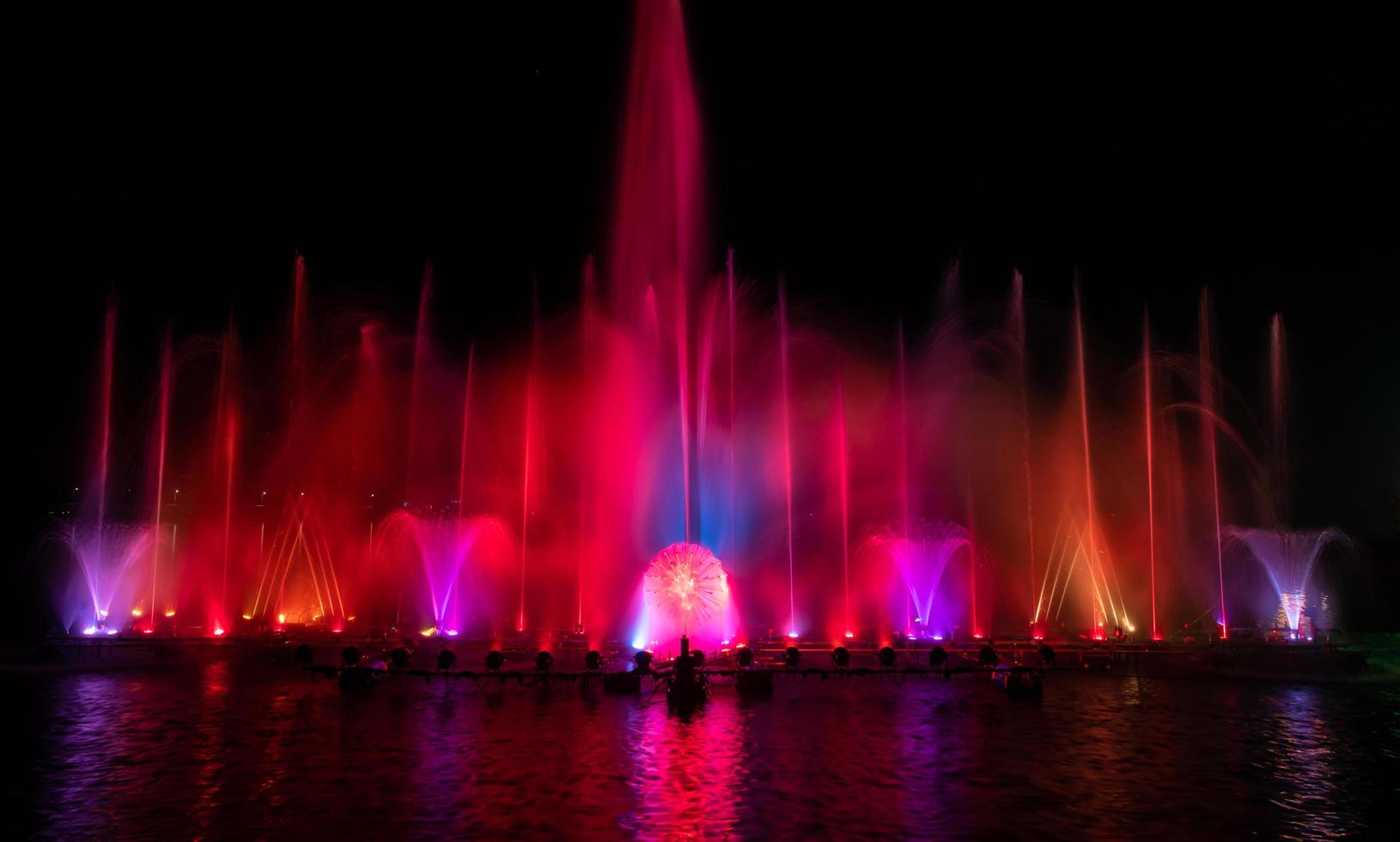 der bunte Springbrunnen tanzt zur Feier des Jahres mit dunklem Nachthimmelhintergrund. foto