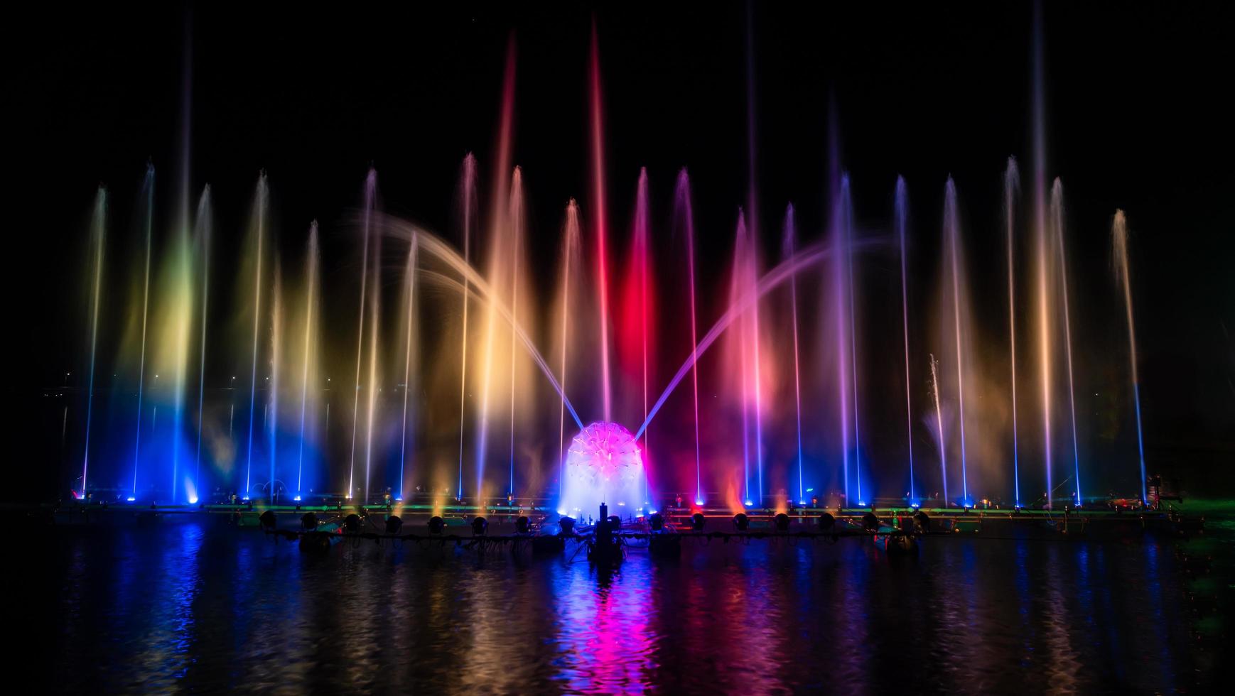der bunte Springbrunnen tanzt zur Feier des Jahres mit dunklem Nachthimmelhintergrund. foto