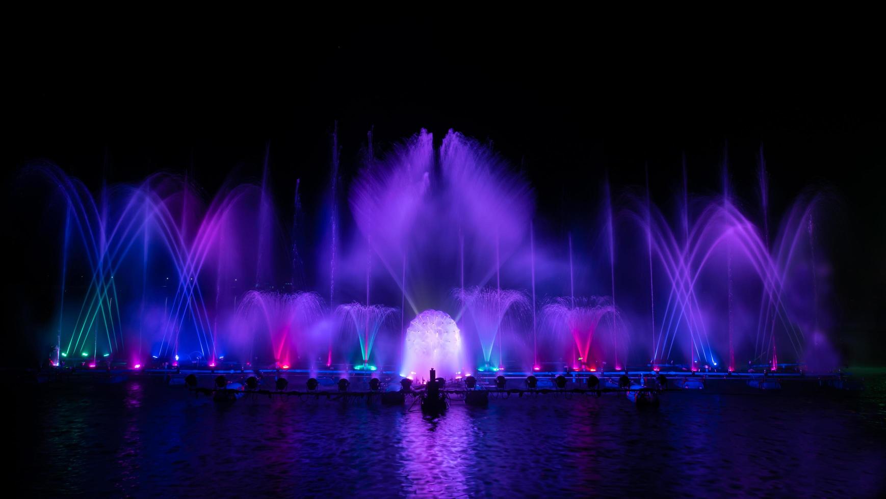 der bunte Springbrunnen tanzt zur Feier des Jahres mit dunklem Nachthimmelhintergrund. foto