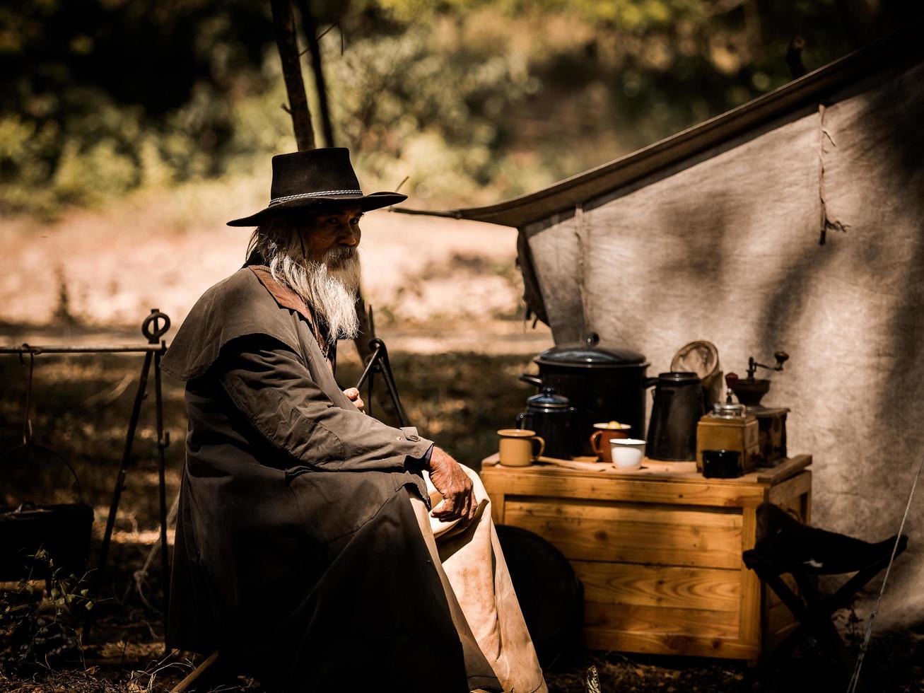 Ein älterer Cowboy saß mit einer Waffe da, um die Sicherheit des Lagers im westlichen Bereich zu bewachen foto