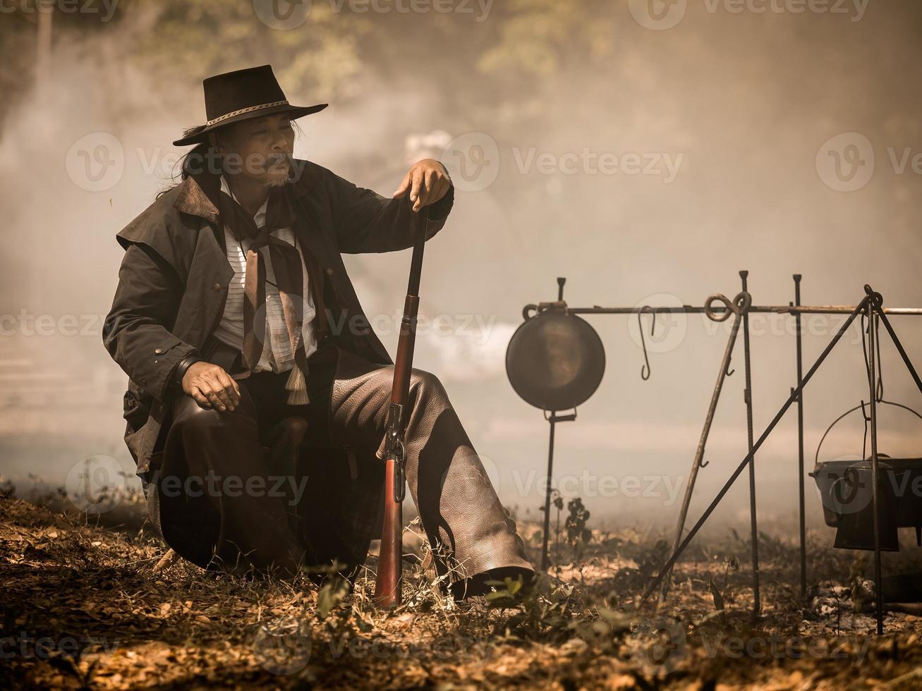 Ein älterer Cowboy saß mit einer Waffe da, um die Sicherheit des Lagers im westlichen Bereich zu bewachen foto