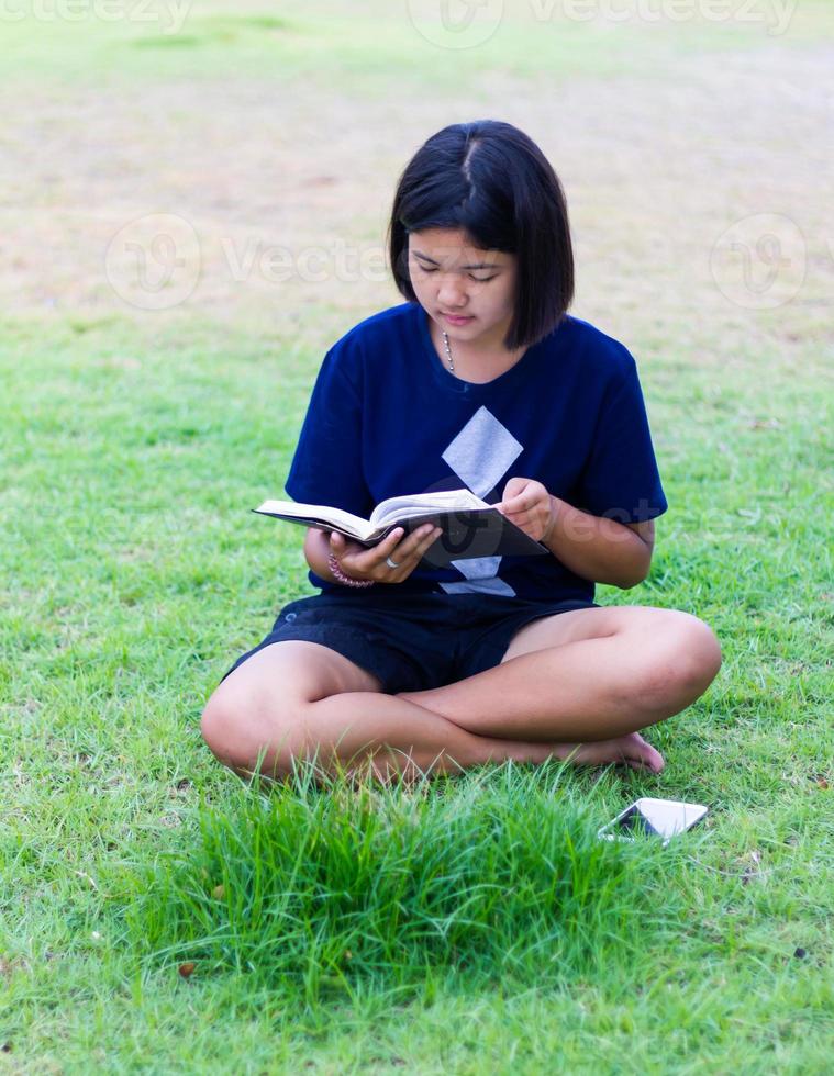 Mädchen liest auf dem Rasen. foto