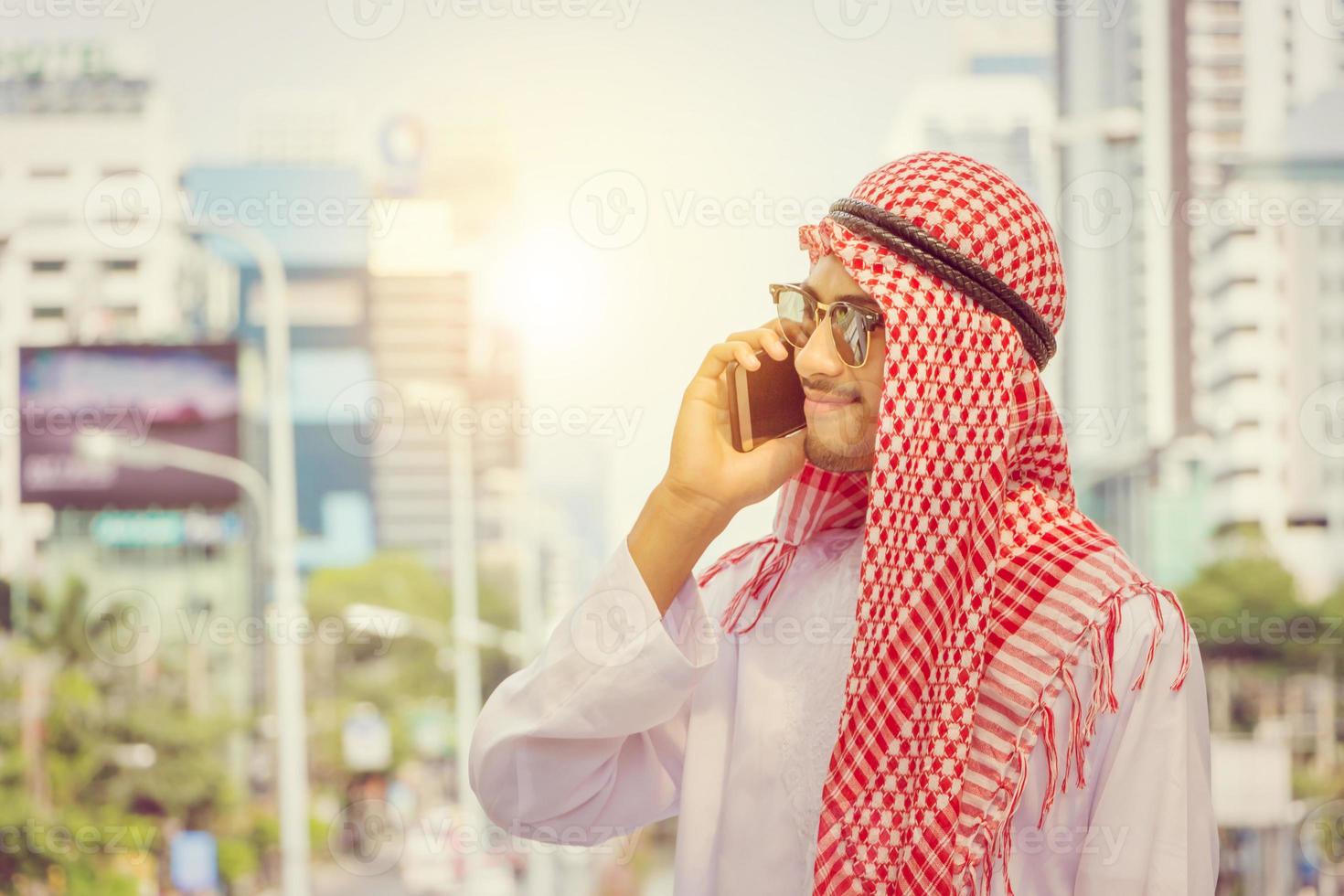 junger arabischer nahöstlicher geschäftsmann, der mobiles smartphone verwendet, verschwommenen stadthintergrund foto