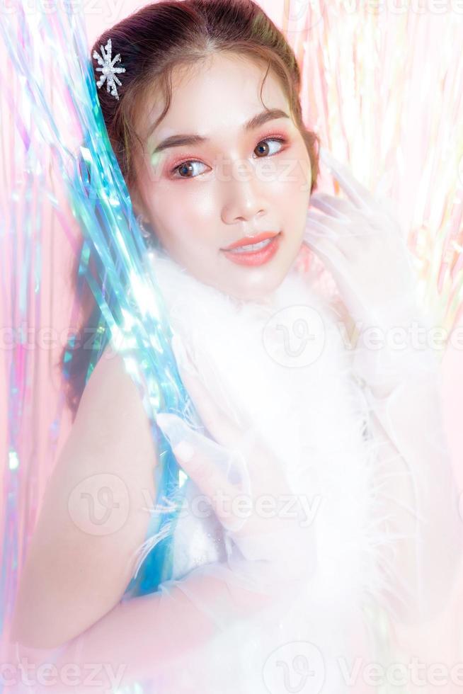 junge asiatische frau mit einem schönen gesicht trägt ein glamourkleid, das von einer regenbogenvorhangparty umgeben ist. Menschen, Urlaub, Emotion und Glamour-Konzept. foto