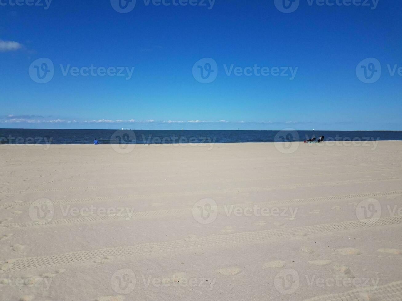 Reifenspuren und Fußabdrücke auf gekämmtem Strand- und Meerwasser foto