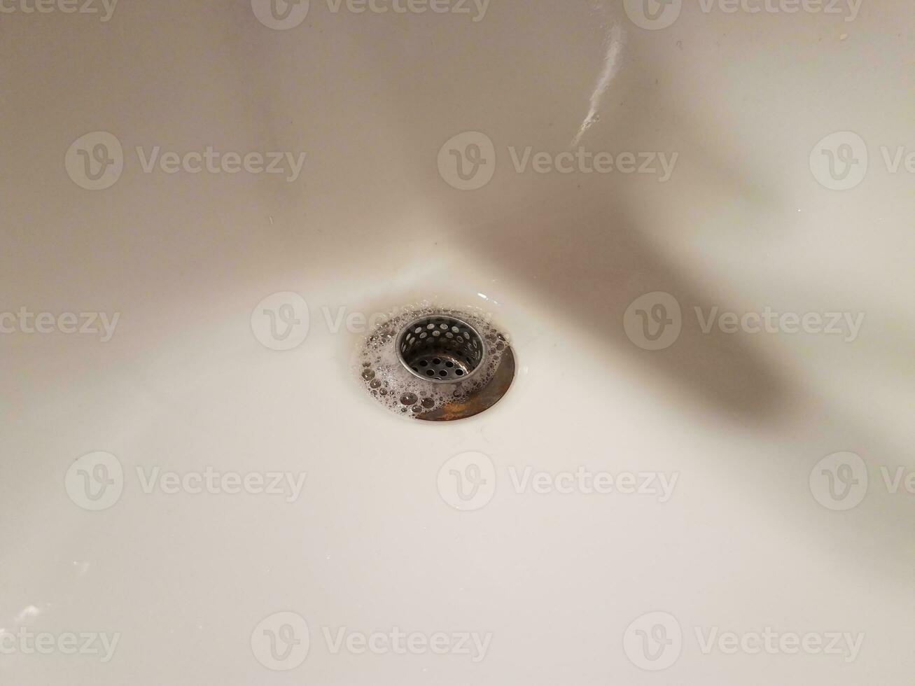 Waschbecken mit Abfluss und Wasser- und Seifenblasen foto