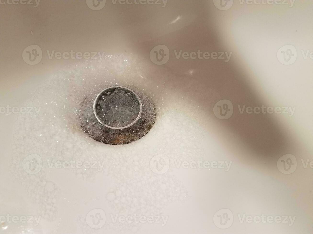 Waschbecken mit Abfluss und Wasser- und Seifenblasen foto