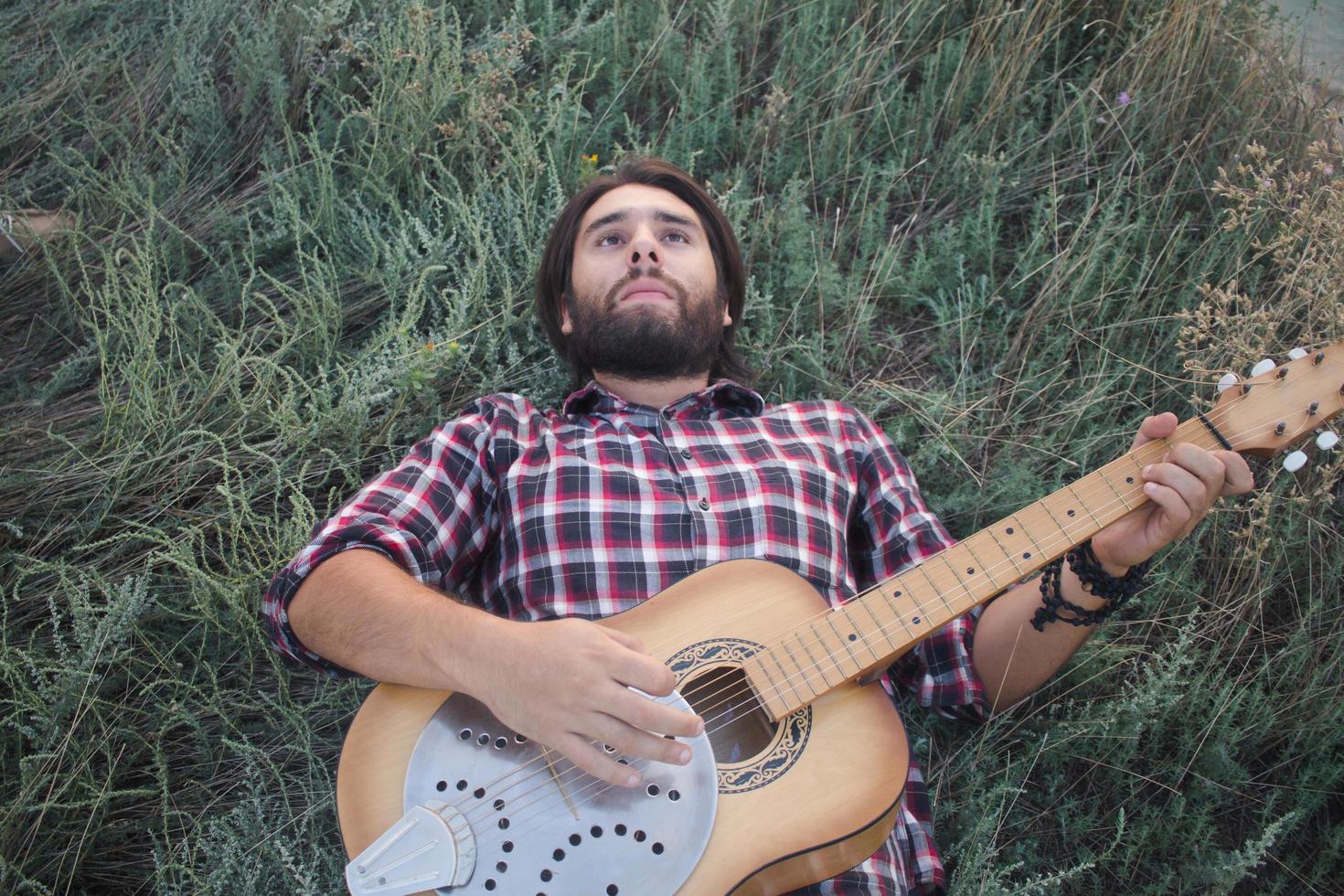 junger Mann mit Akustikgitarre im Freien foto