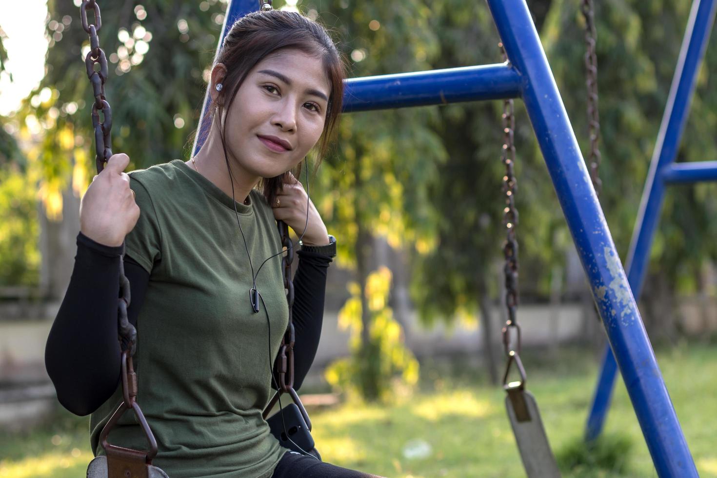 Teenager-Mädchen sitzt lächelnd auf einer Schaukelkette. foto