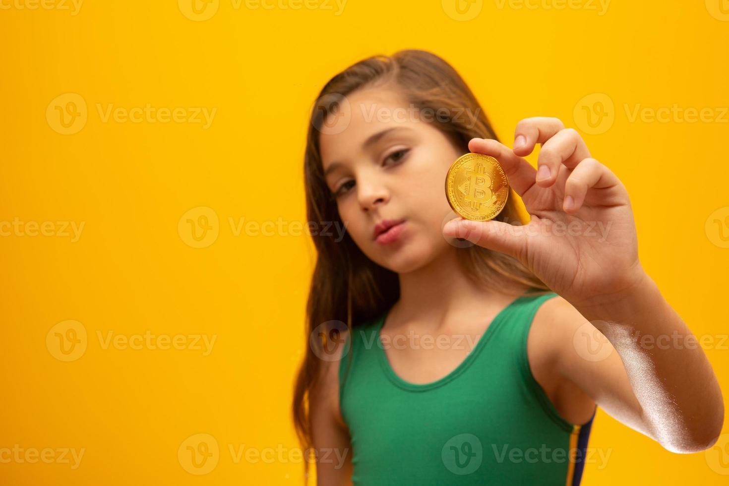 Kind, das Kryptowährung in Metall hält. Goldmünze. golden. auf gelbem Hintergrund. foto