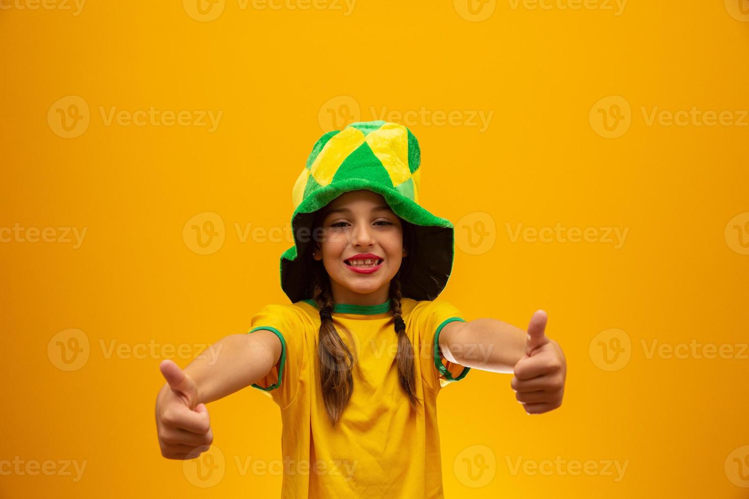 Fußballfan, brasilianische Mannschaft. Weltmeisterschaft. Schönes kleines Mädchen, das ihr Team auf gelbem Hintergrund anfeuert foto