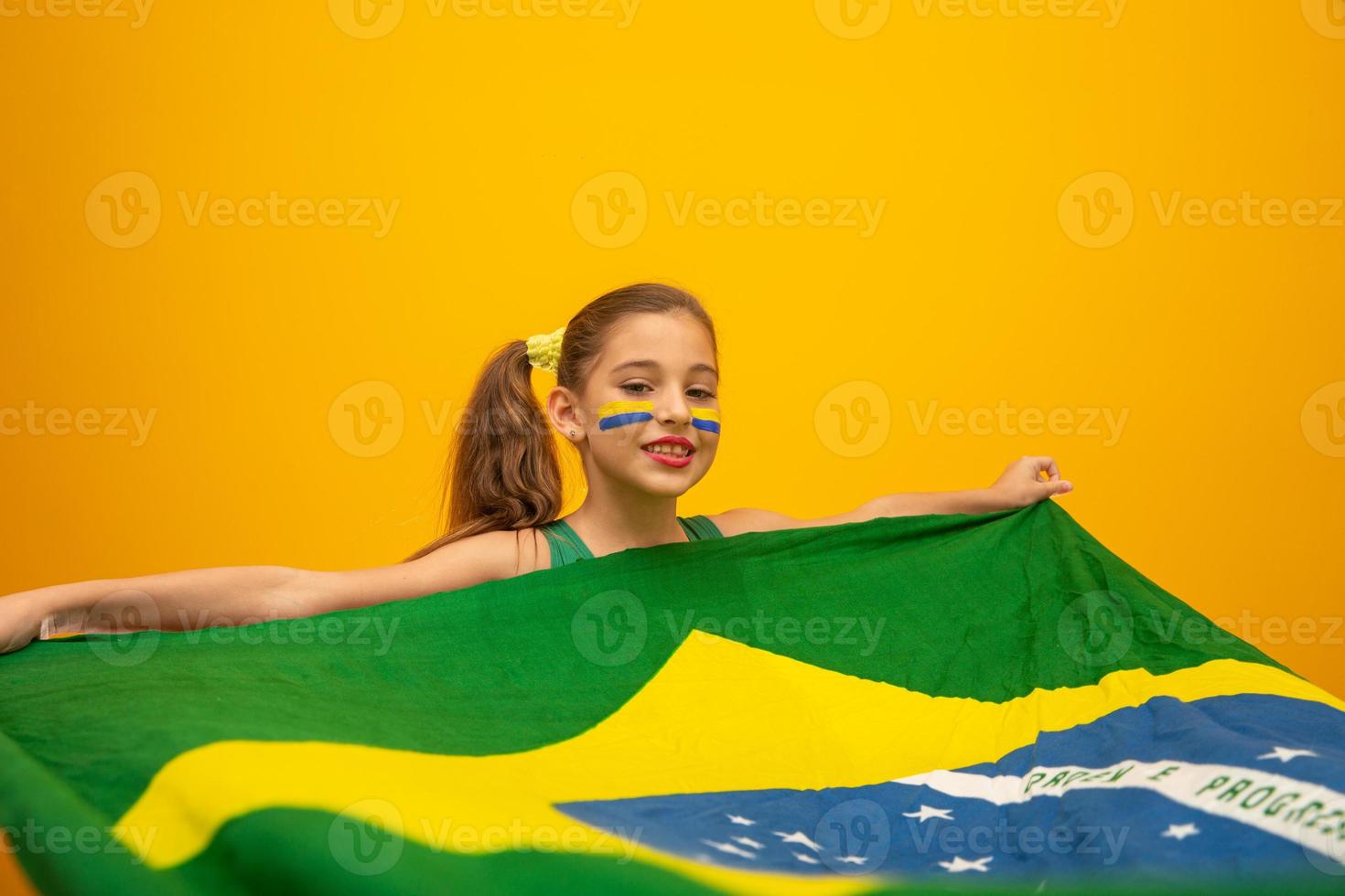 Fußballfan, brasilianische Mannschaft. Weltmeisterschaft. Schönes kleines Mädchen, das ihr Team auf gelbem Hintergrund anfeuert foto