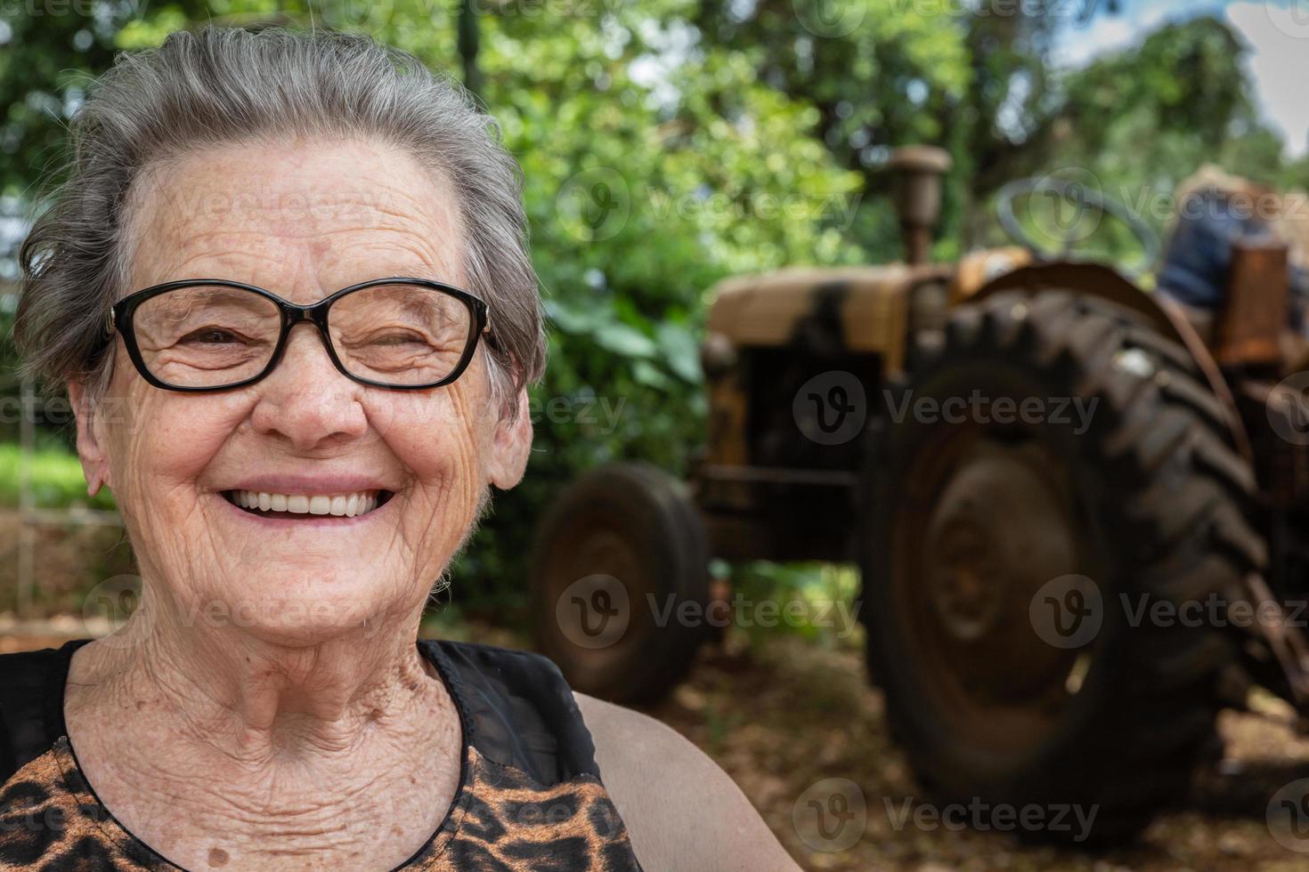 ältere glückliche alte Bäuerin mit Brille, die lächelt und in die Kamera schaut foto