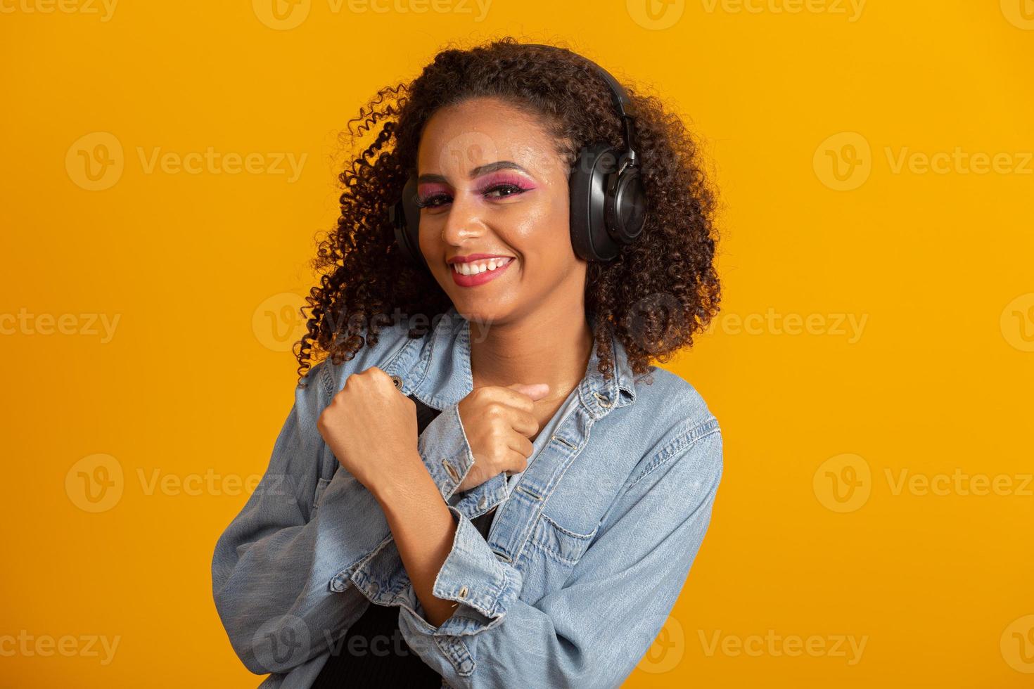 menschen, musik, emotionen konzept. Entzückte sorglose Frau mit Afro-Frisur tanzt im Rhythmus der Melodie, schließt die Augen und hört lautes Lied im Kopfhörer. schöne afro-frau mit ihren kopfhörern foto