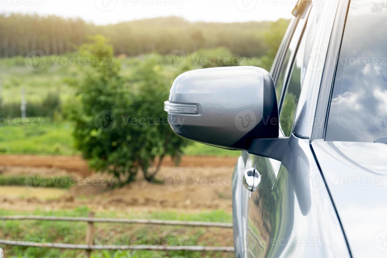 Spiegelflügel eines grauen Autos. Park gegenüber und dahinter ist ein verschwommener Blick auf Natur, Bäume und Gras. Reisen in die Naturgebiete der Provinz. foto