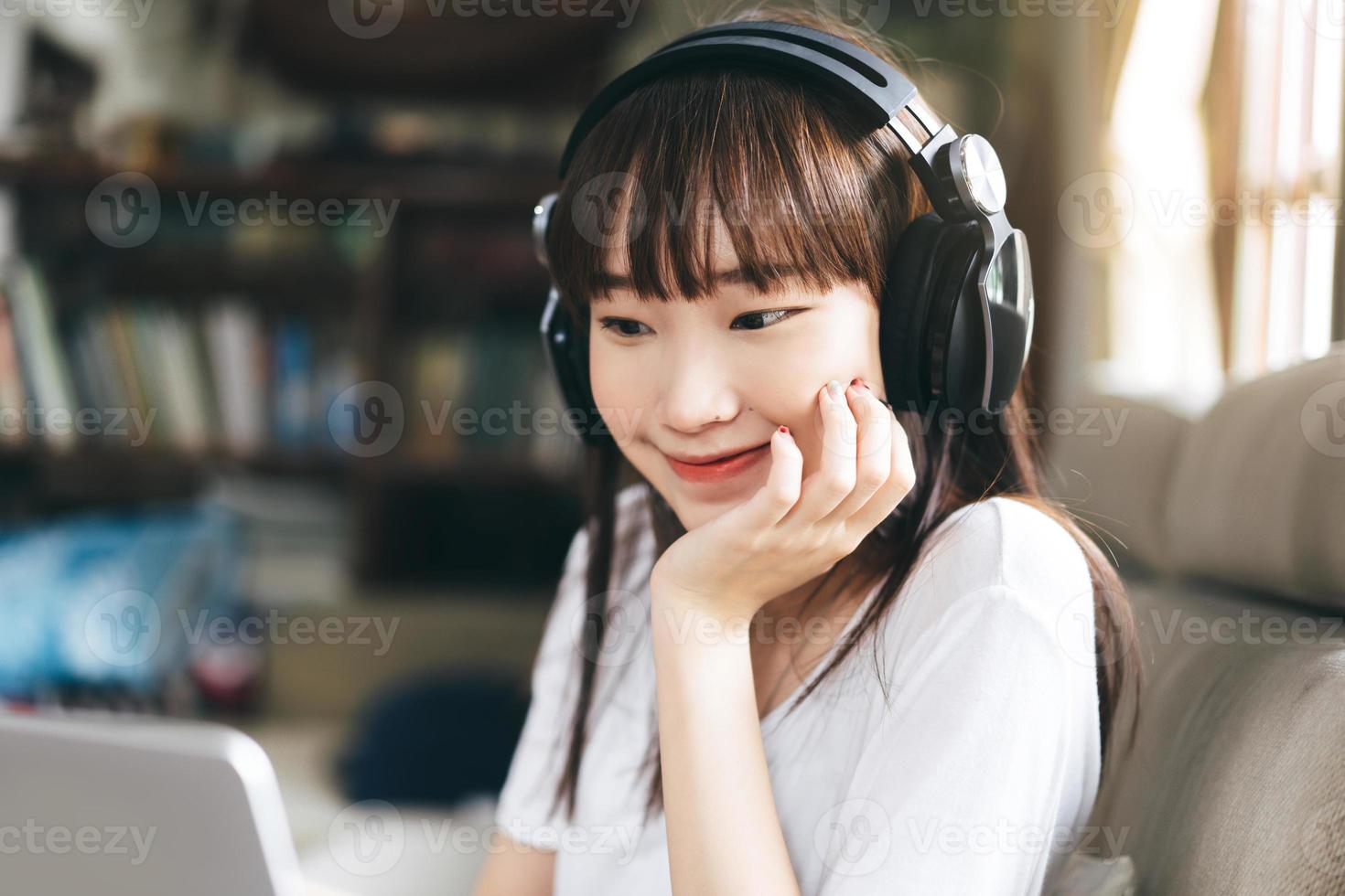 asiatische teenagerfrau hört musik mit kopfhörer zu hause bleiben. foto