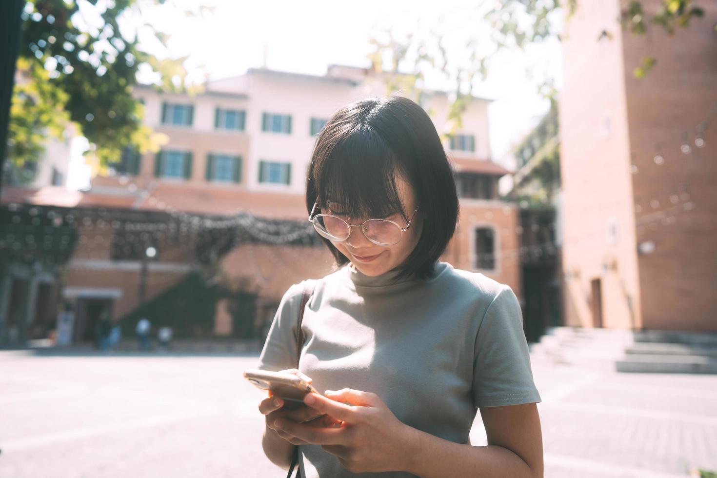 junge erwachsene glückliche asiatische frau trägt brillen mit handy für soziale medien. foto