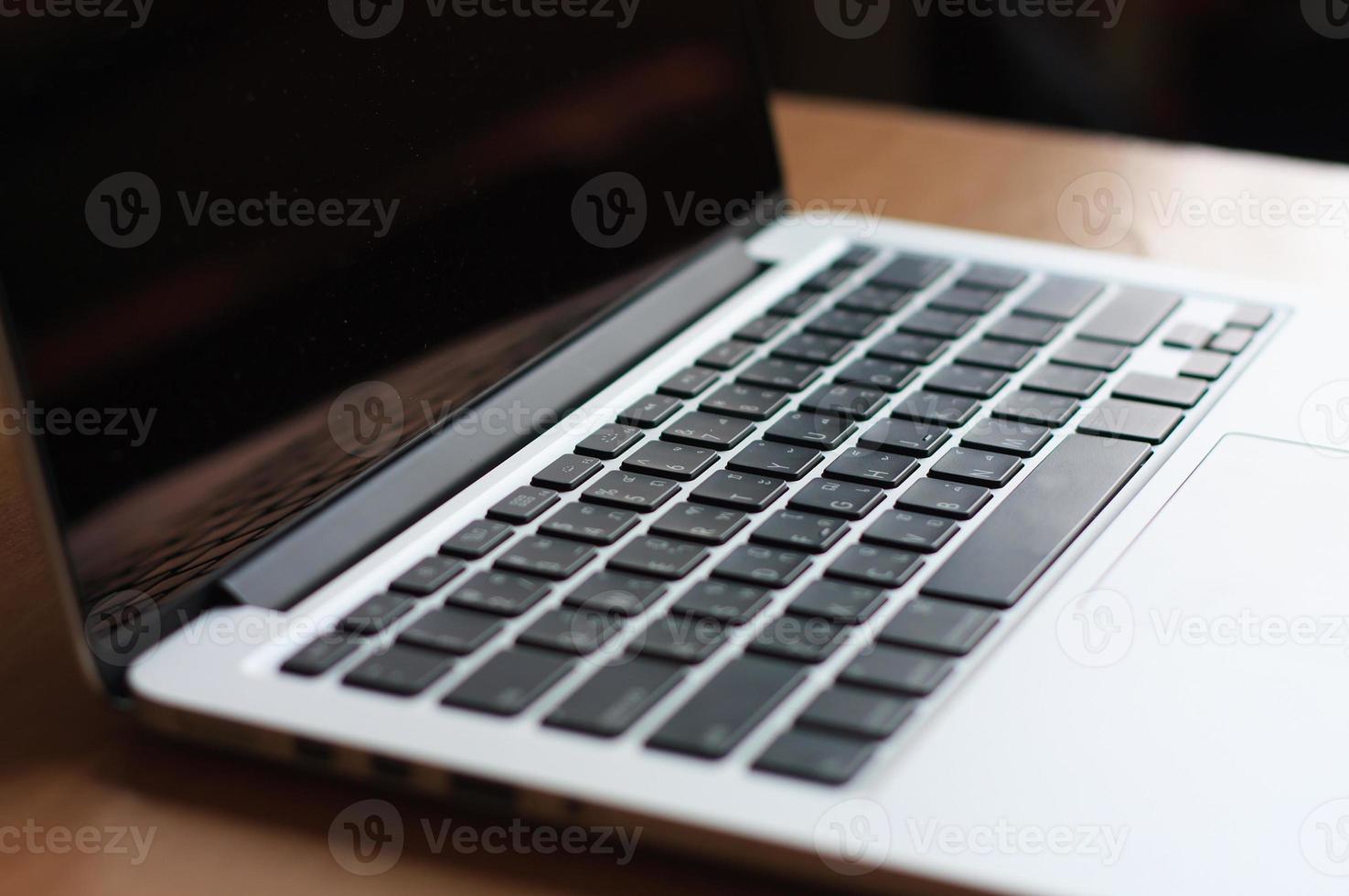 offener laptop mit schwarzem bildschirm auf modernem holzschreibtisch foto