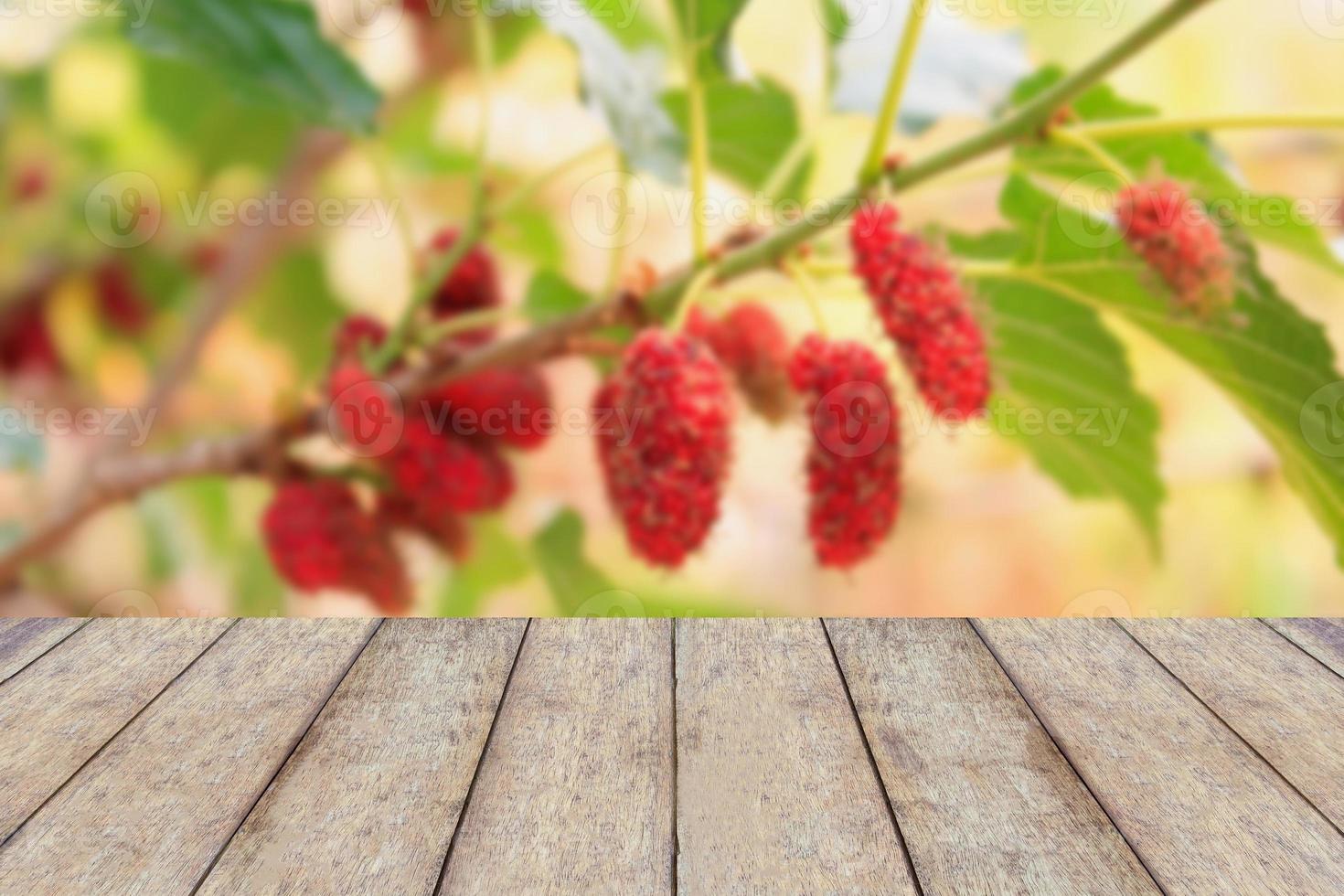 Holztisch mit rotem Maulbeerhintergrund foto