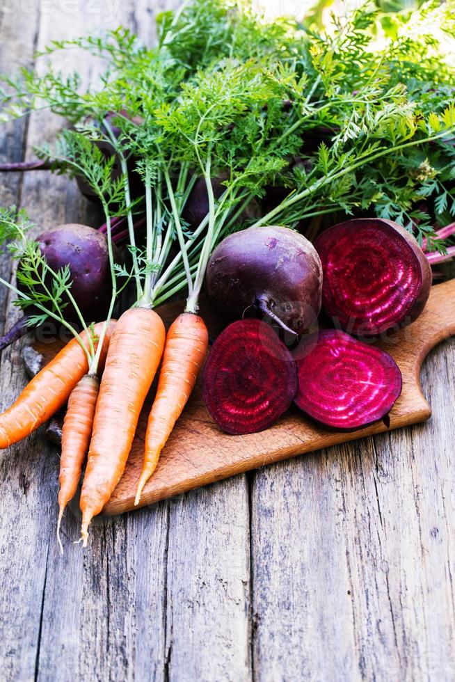 frische Rüben und Karotten auf hölzernem Hintergrund foto