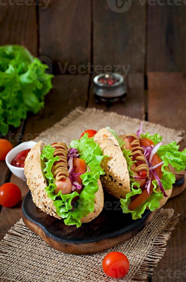 Hotdog mit Ketchup-Senf und Salat auf hölzernem Hintergrund. foto