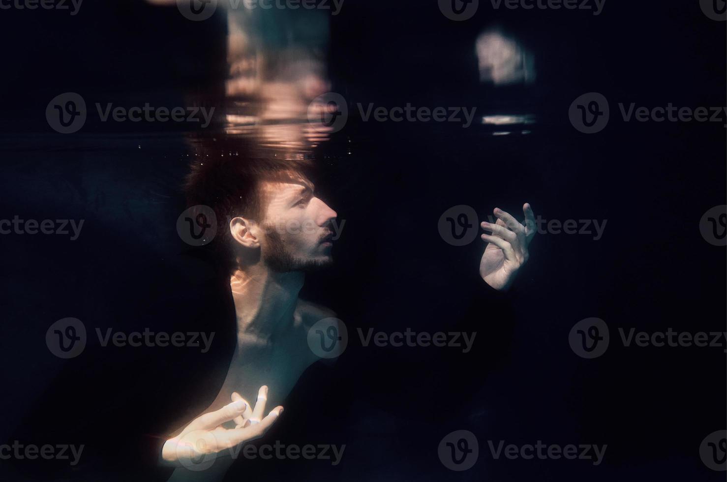 Mann in einem Schwimmbad unter Wasser auf schwarzem Hintergrund foto