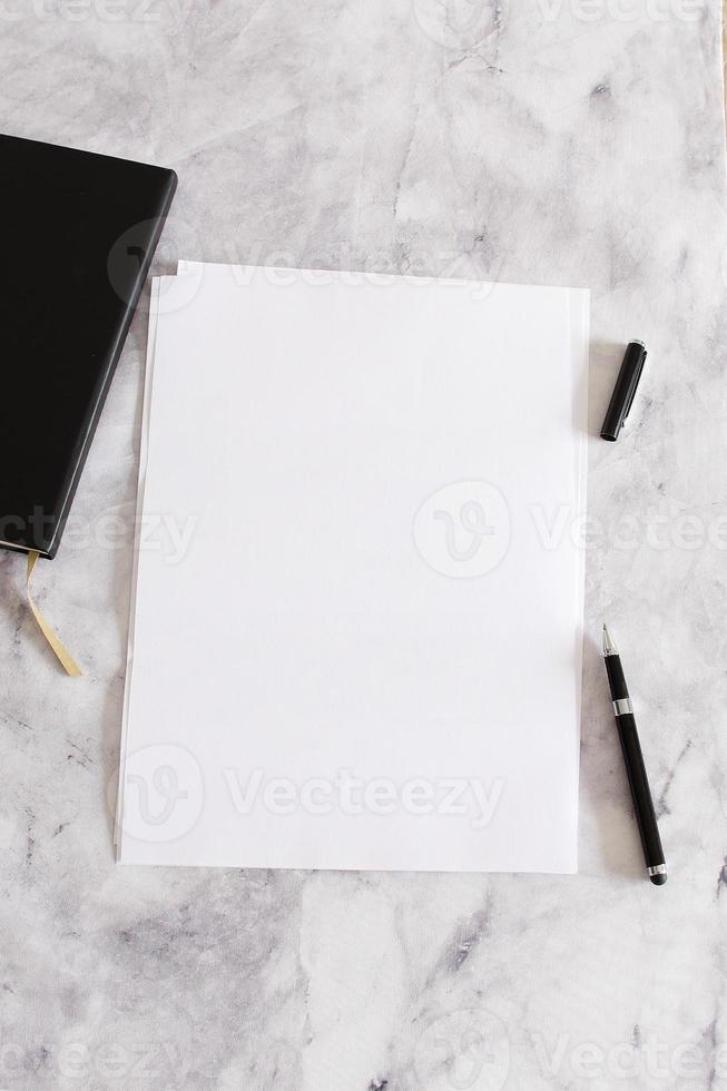 a4 weißes leeres papier auf marmorhintergrund mit stift und notizbuch, modell foto