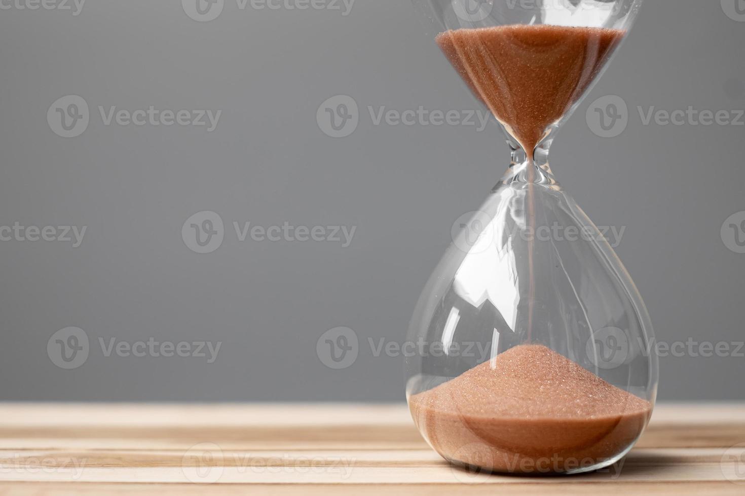 sanduhr auf tisch büro mit kopierraum, sand fließt durch die sandglasbirne und misst die verstreichende zeit. countdown, frist, lebensdauer und ruhestandskonzept foto