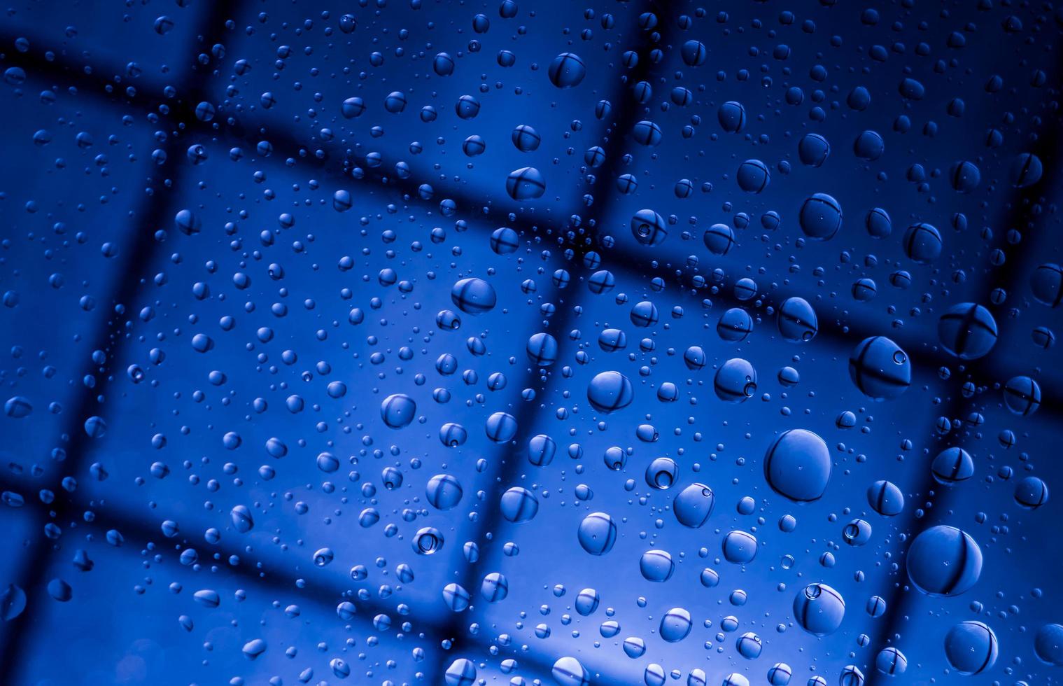 blauer abstrakter unschärfehintergrund mit wassertropfen und reflexion auf transparentem glas. blauer hintergrund für einsame, traurige und vermisste jemanden am regnerischen tageskonzept foto