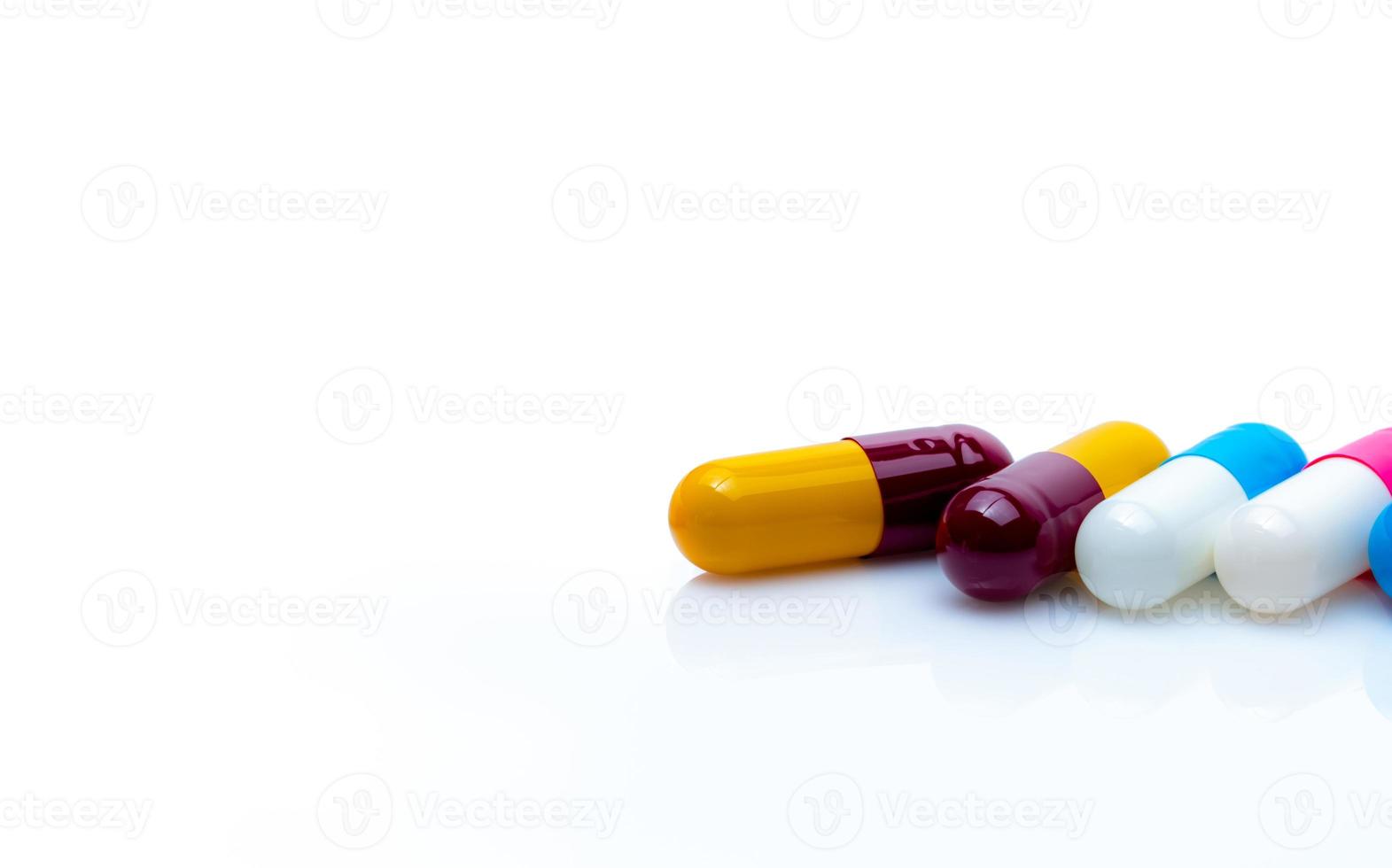 Antibiotische Kapselpillen auf weißem Hintergrund. Resistenz gegen Antibiotika. rot-gelbe, blau-weiße und rosa-weiße antibiotische Kapselpillen. verschreibungspflichtige Medikamente. Apothekenbanner. pharmazeutische Produkte. foto