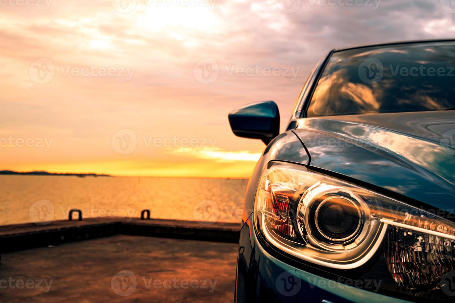 blaues kompaktes suv-auto mit sport und modernem design, das bei sonnenuntergang auf einer betonstraße am meer geparkt ist. umweltfreundliche Technologie. Geschäftserfolgskonzept. foto