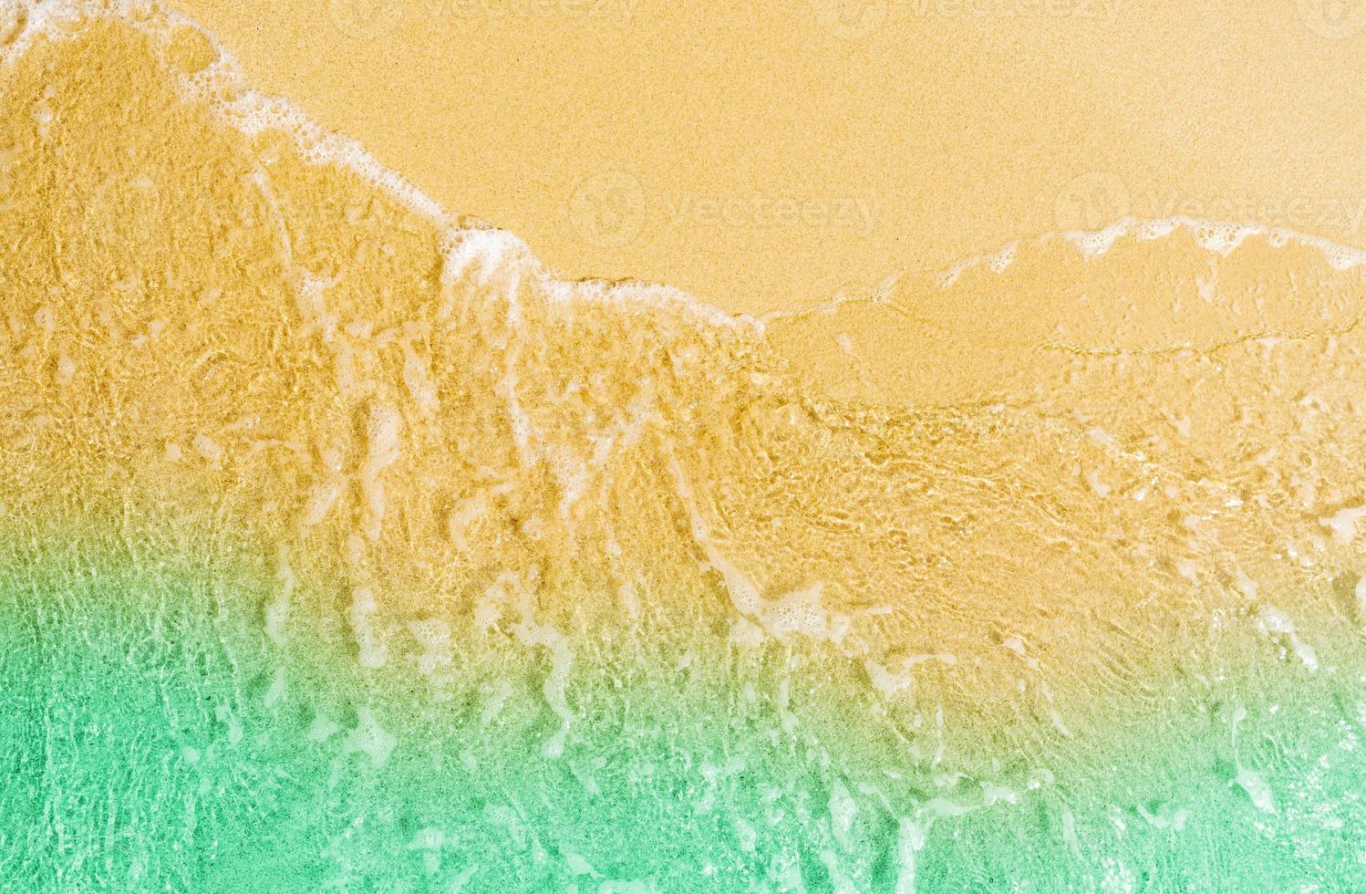 Blick von oben auf den goldenen Sandstrand am Meer mit smaragdgrünem Meerwasser. sommerferien auf tropischem paradiesstrandkonzept. Wasserspritzer am Sandstrand. sommergefühl. foto