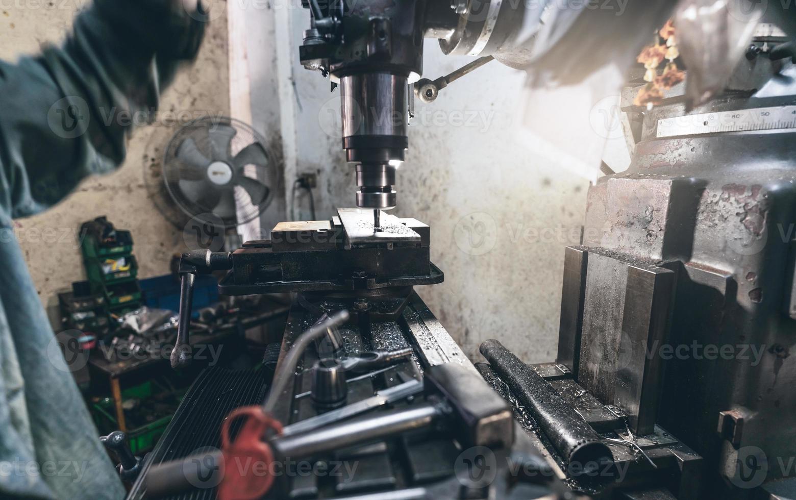 selektiver Fokus auf Fräsmaschine. Der unscharfe Arbeiter arbeitet an einer Fräsmaschine, um Metallplatten zu fräsen. Werkzeug zum Schneiden von Metallwerkstücken. Fabrik zur Herstellung von Stahl. Mahlvorgang. Maschine in der Werkstatt foto