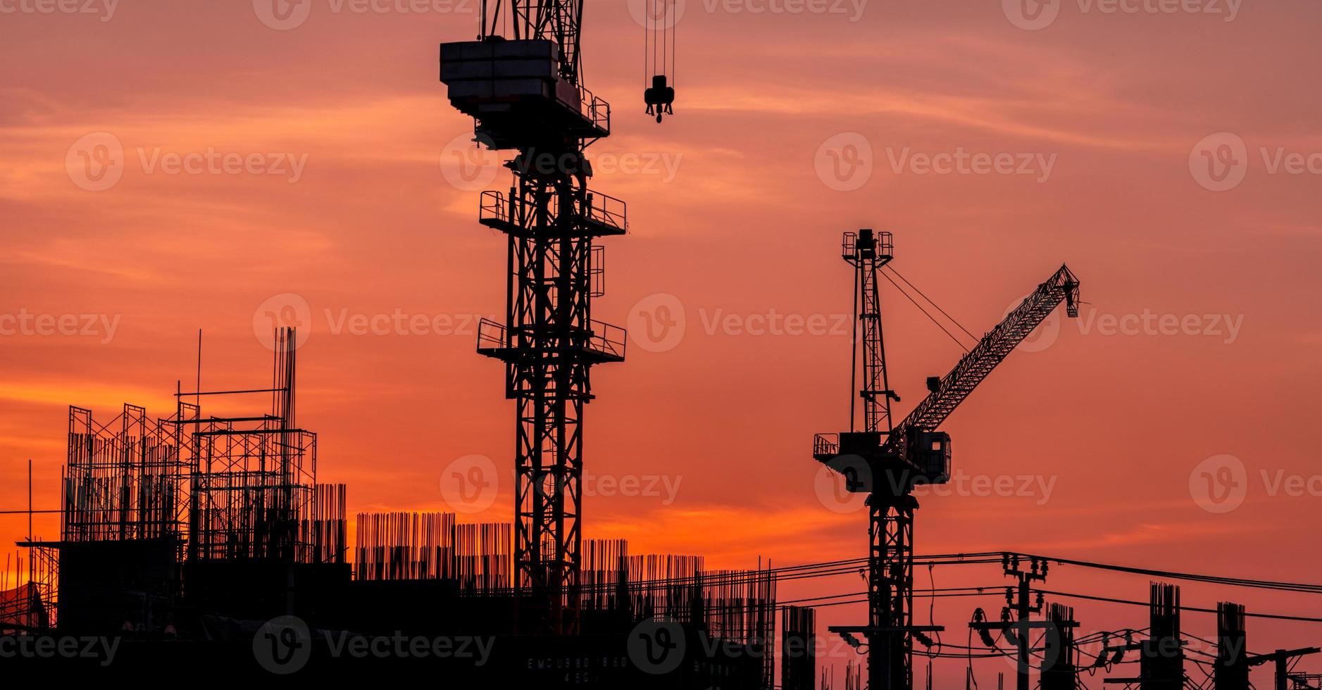 baustelle mit kran und sonnenunterganghimmel. Immobilienwirtschaft. kran verwenden rollenhebegeräte auf der baustelle. Gebäude aus Stahl und Beton. kranarbeit gegen orangefarbenen sonnenunterganghimmel. foto