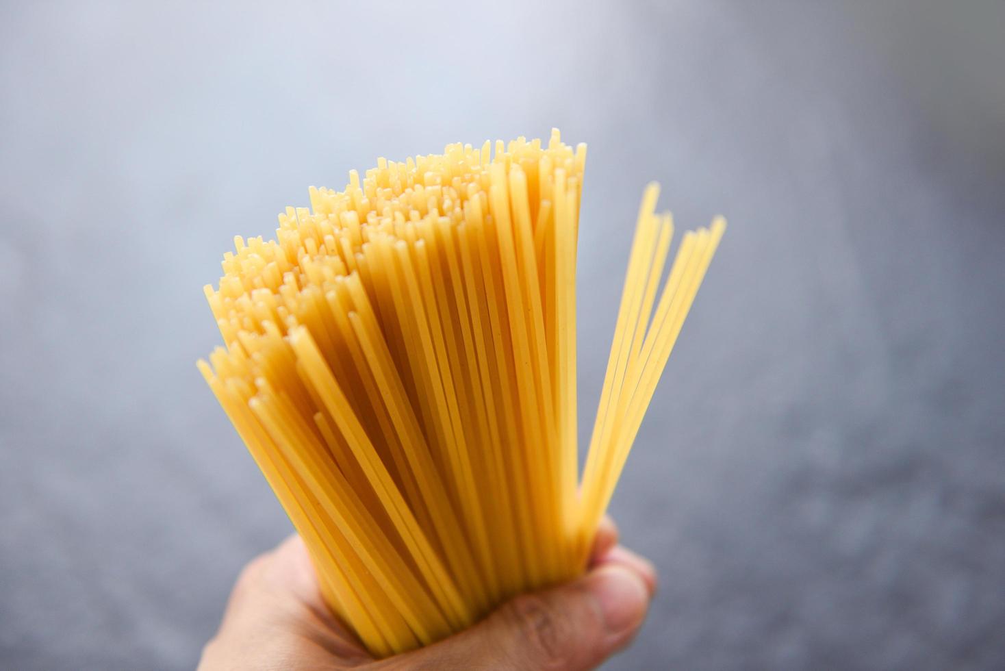 Mann, der rohe Spaghetti italienische Pasta hält, ungekochte Spaghetti gelb, lange bereit, im Restaurant italienisches Essen und Menü zu kochen? foto