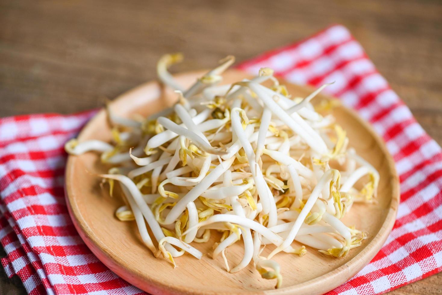 bohnensprossen auf holzplattentischhintergrund in der küche, rohe weiße organische bohnensprossen oder mungbohnensprossen für vegane lebensmittel foto