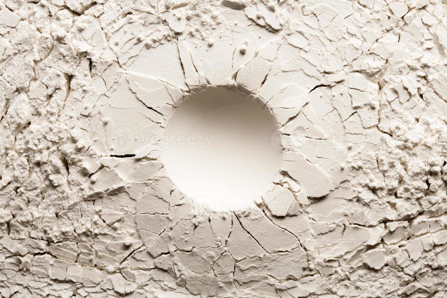 runder Krater auf weißem Hintergrund mit Riss. rissiger hintergrund mit einem runden loch. foto