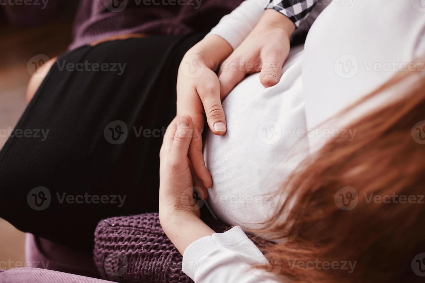 junges Paar erwartet Baby, das Bauch umarmt. Schwangerschafts- und Personenkonzept foto