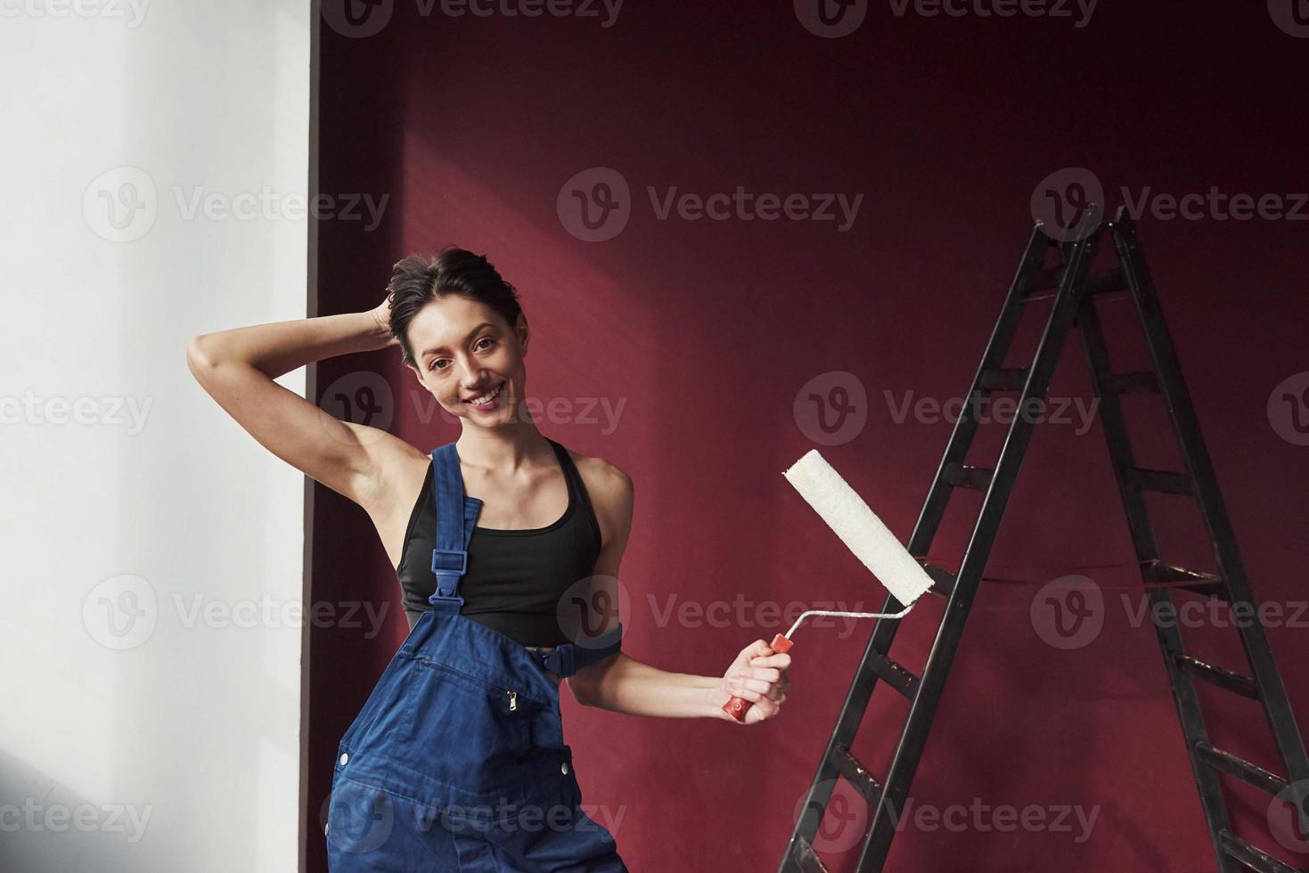 Hier ist Ihre perfekt gemachte Arbeit. Junge Hausfrau beschloss, in ihrem neuen Haus Tapeten in das Zimmer zu kleben foto