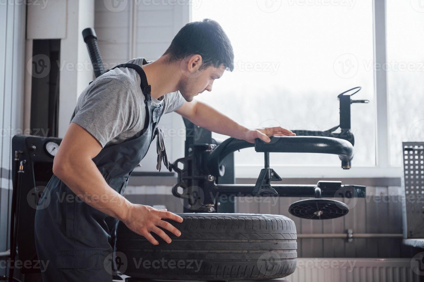 Einsetzen des Elements in den Reifen. junger mann arbeitet tagsüber mit radscheiben in der werkstatt foto