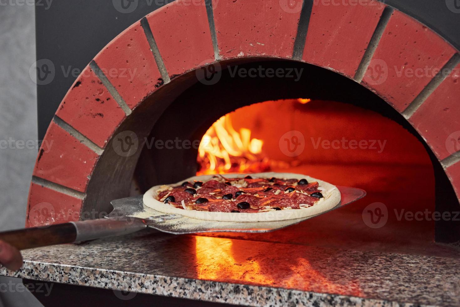 Pizza hineinlegen. Feuer, das im Ofen brennt. Nahaufnahme von Holz in Flammen foto