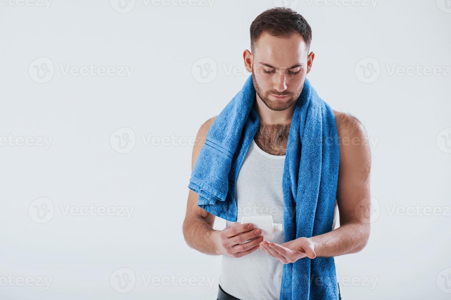 Hautpflegekonzept. Mann mit blauem Handtuch steht vor weißem Hintergrund im Studio foto