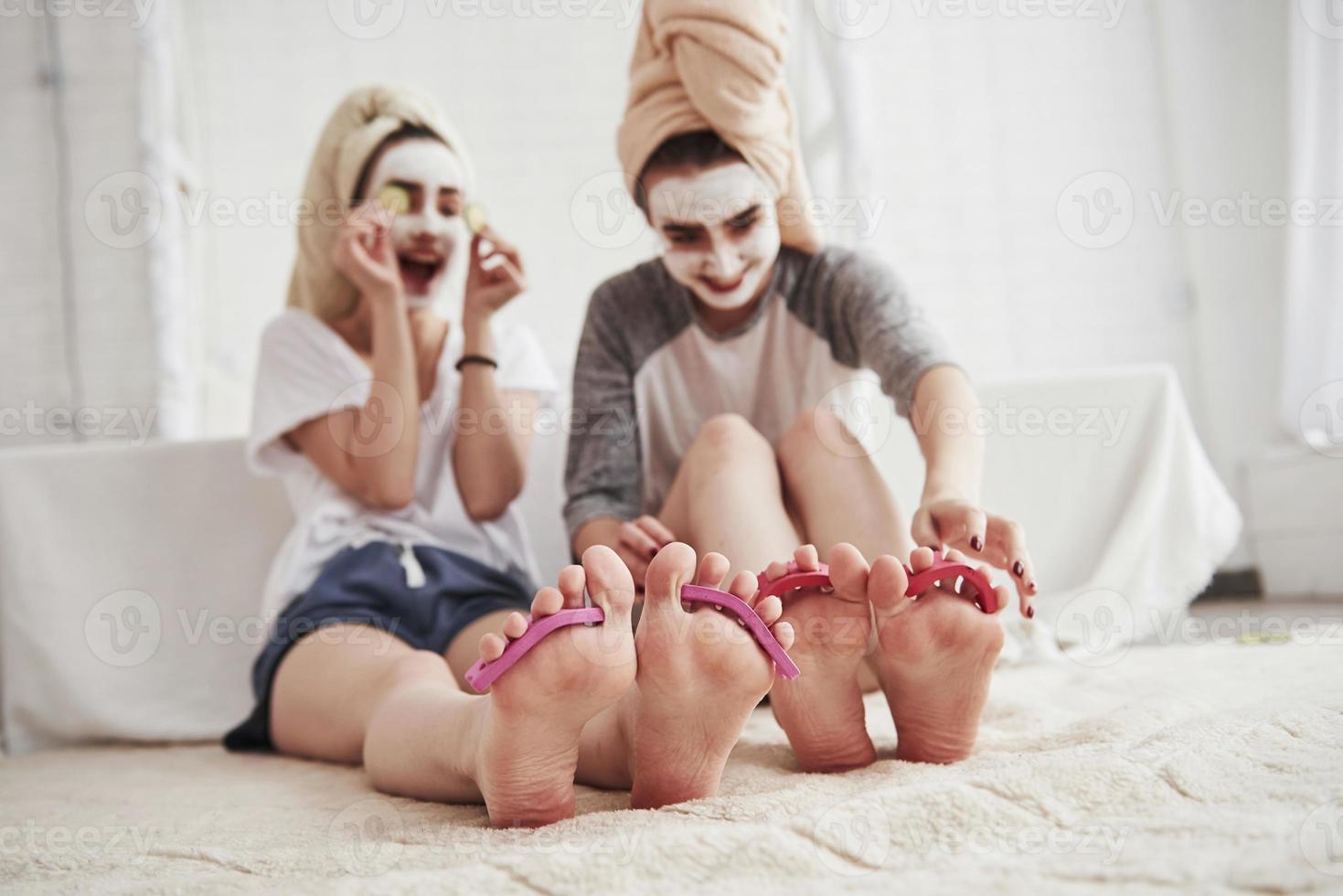 Zeit zum Abnehmen. Pediküre und lackierte Beinnägel. konzeption der hautpflege mit weißer maske und gurken im gesicht foto