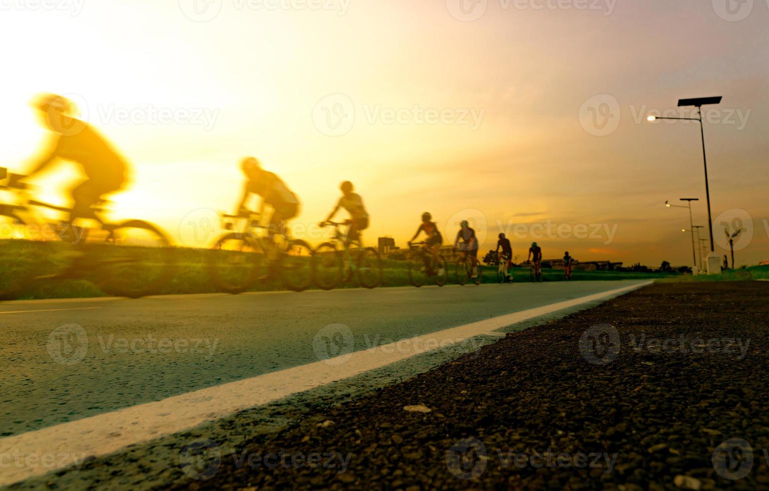 verwischen Sie Fotosportler fahren Fahrräder mit Geschwindigkeitsbewegung auf der Straße am Abend mit Sonnenunterganghimmel. Sommerübungen im Freien für ein gesundes und glückliches Leben. radfahrer, der mountainbike auf radweg fährt. Team. foto